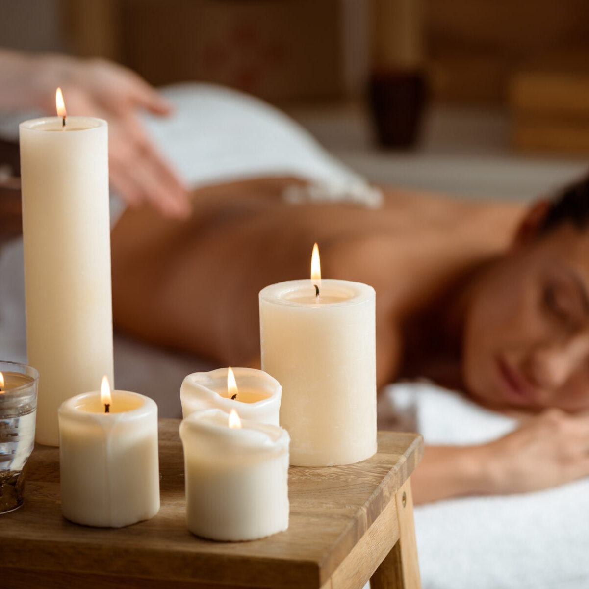 Young beautiful brunette girl relaxing in spa salon. Eyes closed. Focus on candles. Copy space.